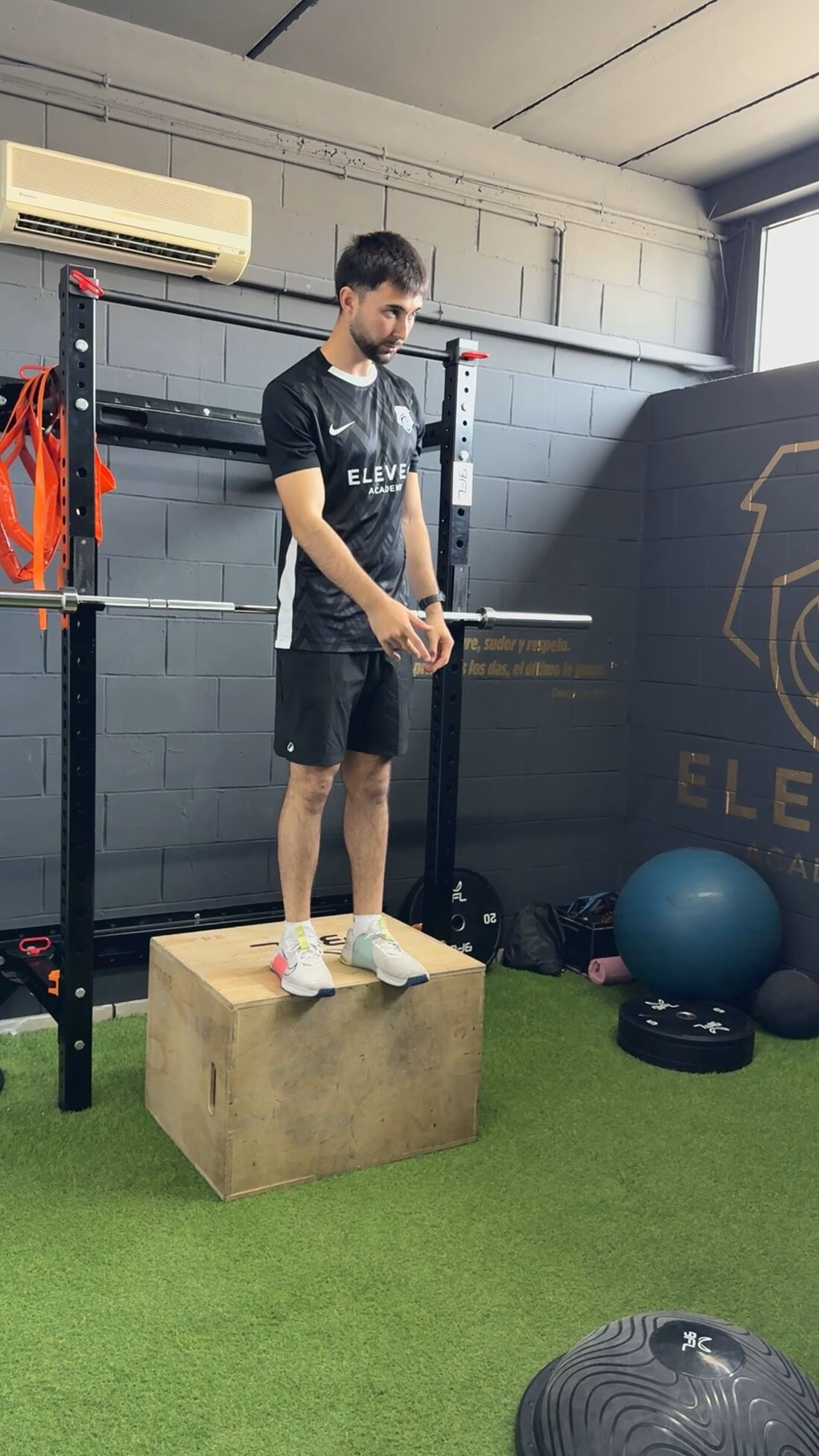 Jugador trabajando con arnés en la plataforma de fuerza mientras el preparador corrige