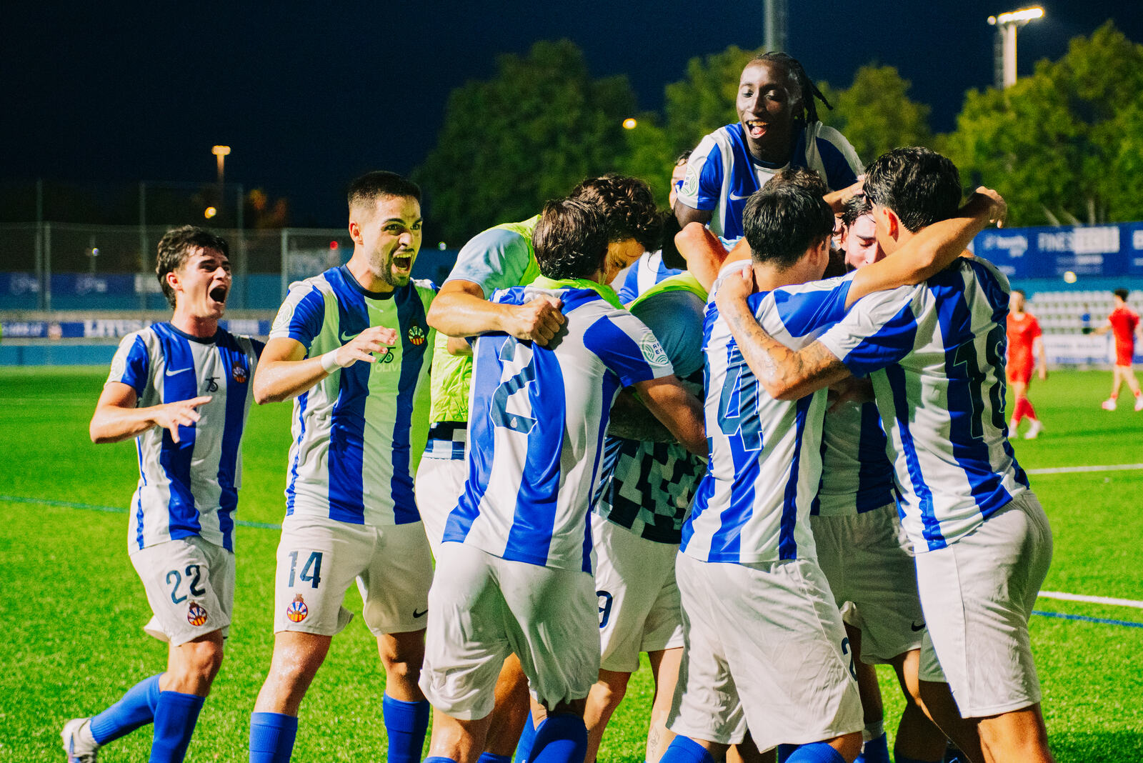 Jugadores celebrando un gol en el campo durante un partido nocturno